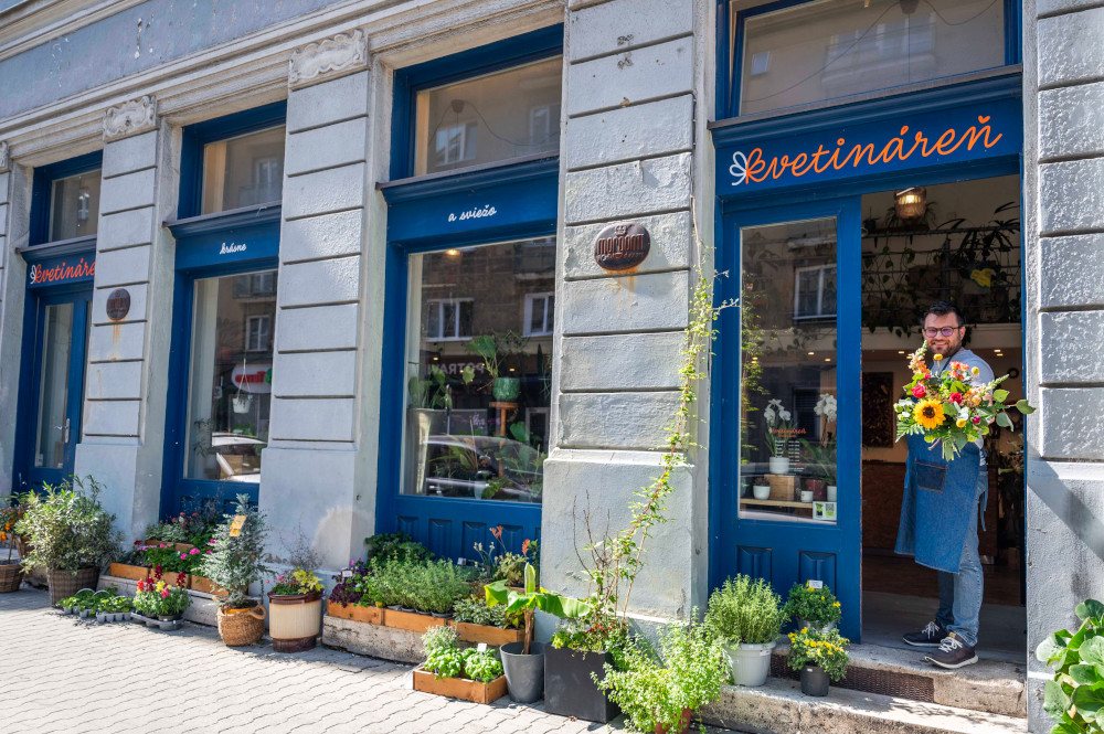 Predajňa Kvetináreň na Medenej 17 v Bratislave — florista s kyticou vo dverách